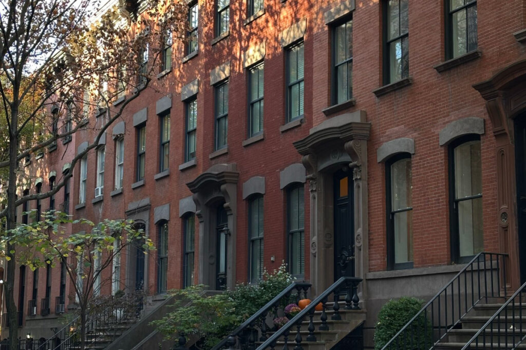 Prewar brownstone walk-up apartment buildings on a tree-lined street in Washington Heights, Manhattan